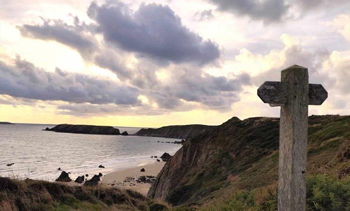 View onto Marloes sands and the Pembrokeshire Coast path, with a wooden sign